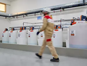 Homme qui marche à côté de bidons de produits chimiques Hydrex