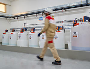 Homme qui marche à côté de bidons de produits chimiques Hydrex